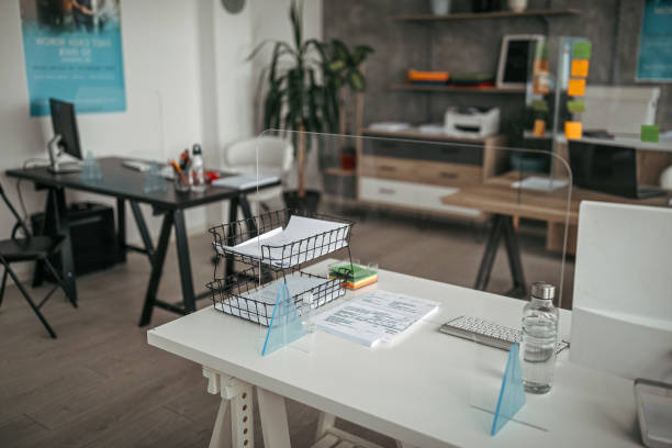 Acrylic glass partition on desk Interior of modern office with acrylic glass partition on desk. Acrylic glass wall - protection against coughs and spitting, protection against viruses. workplace absence stock pictures, royalty-free photos & images