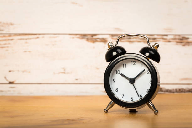 istock Black retro alarm clock with bells on a wooden table, daily routine concept. ten hours 10 minutes 1227206844