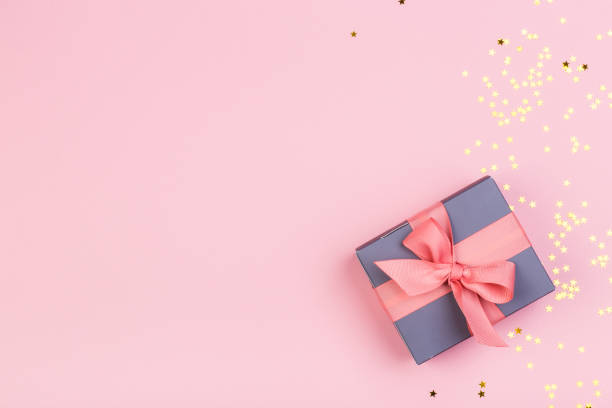 istock Gift or gift box and stars confetti on a pink table from above. Flat composition for birthday, mothers day or wedding. 1227206906