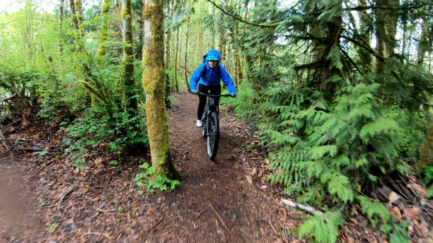 istock Female mountain biker rides e-bike along forested path 1227208287