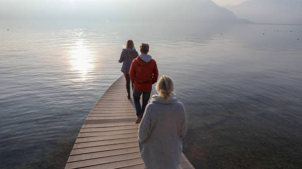 istock Three people walk along curving lake pir, in winter 1227218578