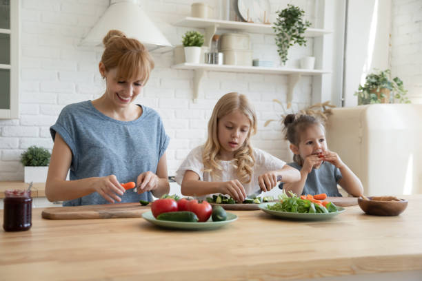 istock Caring mother teaching two little children top use knife. 1227218612