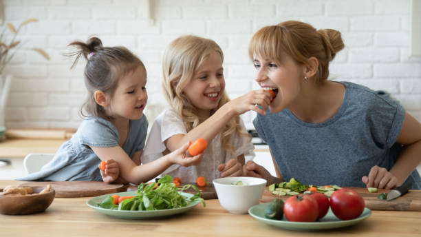 istock Caring daughter feeding mother teaching little children. 1227218614
