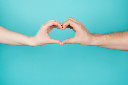 Cropped close-up photo of woman and man making heart with their hands isolated on blue teal bright color background