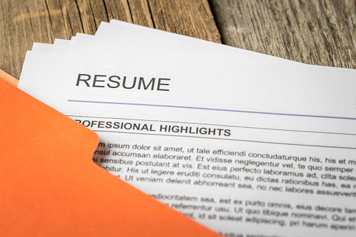 Stock photograph of job resume inside orange folder.