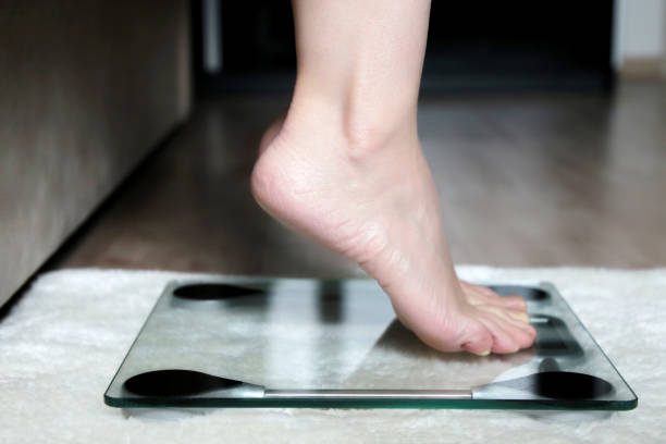 istock Slimming and diet, barefoot female legs on electronic scales 1227223595