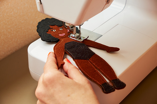 Handmade sewing toy dark-skinned girl. Felt doll with black hair. Mom's workplace.