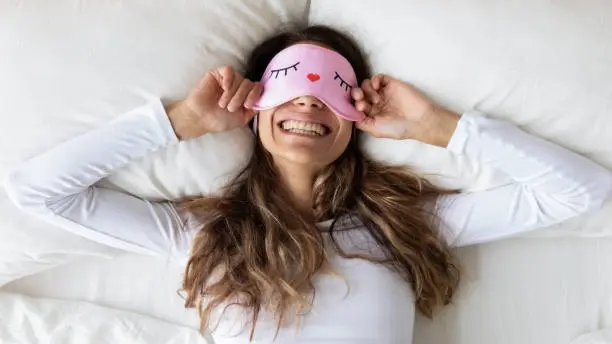 Photo of Top view happy woman wearing funny sleeping mask enjoying morning
