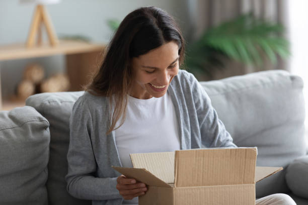 istock Smiling young woman unpacking parcel, opening cardboard box 1227225946