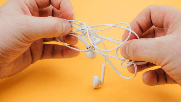 istock man untangles headphones, on a yellow background. close up 1227226145