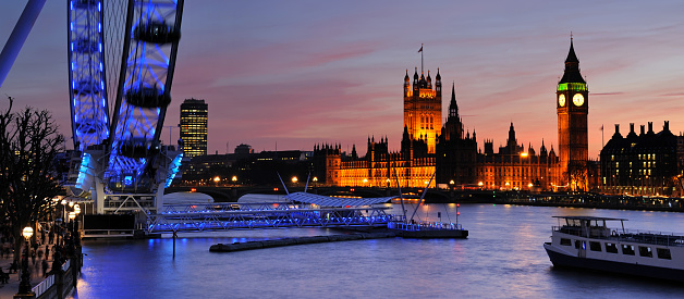 London, England, UK - 24th February 2011: The Houses of Parliament and London Eye across the River Thames, illuminated at dusk. The Houses of Parliament is the meeting place for the House of Commons and the House of Lords.