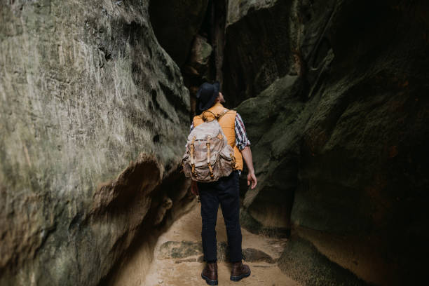 istock Young man hiking at mountain rock with backpack, orange jacket. Travel concept 1227229454
