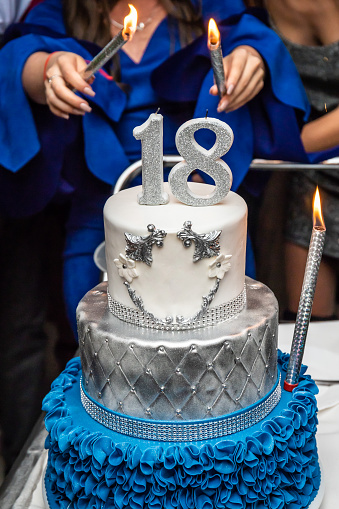 Girl holding firework sticks on the 18 birthday party. Birthday cake with number 18.