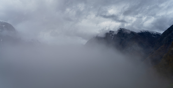 High mountain peaks covered with dense fog in Norway