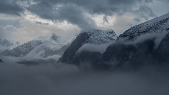 High mountain peaks covered with dense fog in Norway