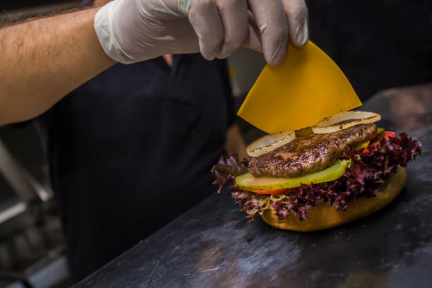 chef adding cheese to hamburger