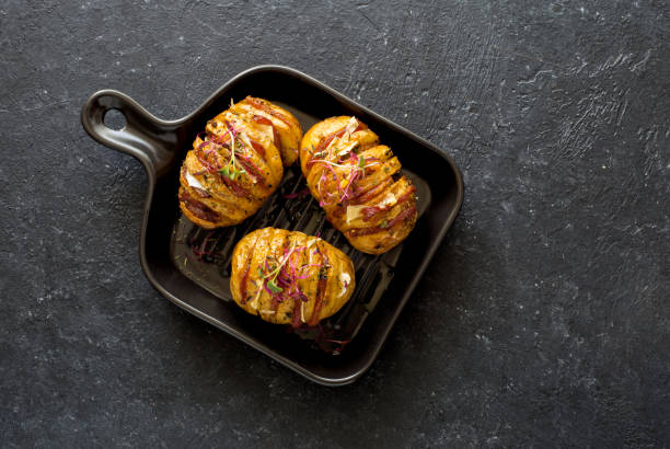 Potatoes baked with bacon, cheese and olive oil served on black plate stock photo