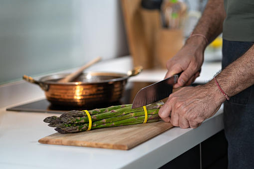 fresh Asparagus on kitchen with man hand, chef cutting asparagus.