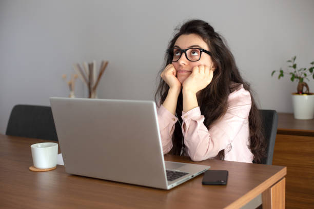 Woman Looking Upward While Sitting in front of the laptop stock photo