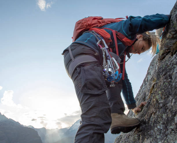 young woman climbs steep rock wall on belay - rock pinnacle cliff mountain peak imagens e fotografias de stock