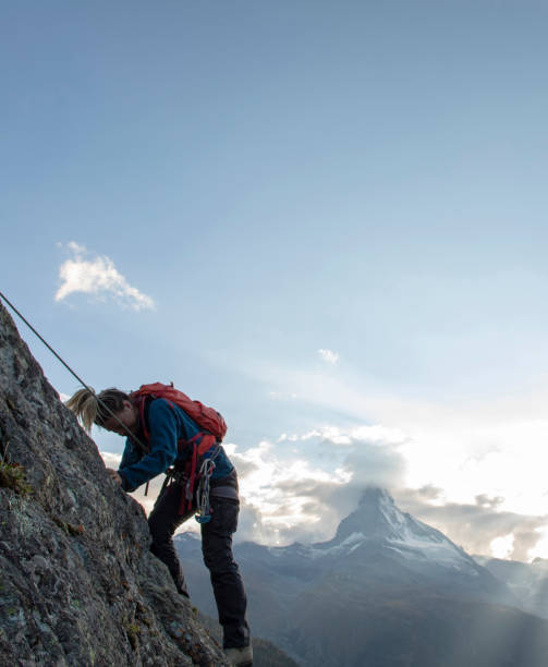 istock Young woman climbs steep rock wall on belay 1227237791