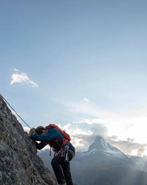 young woman climbs steep rock wall on belay - rock pinnacle cliff mountain peak imagens e fotografias de stock