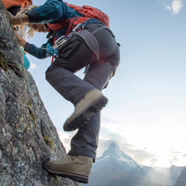 istock Young woman climbs steep rock wall on belay 1227238041