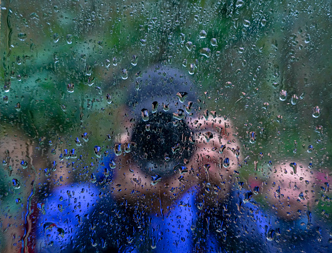 Unrecognizable man silhouette reflection on a wet window. Photographer taking selfie on a mirror.