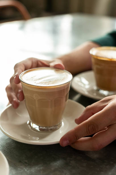 istock Vertical frame, side view - men's hands on both sides holding a transparent glass full of coffee, standing on the bar counter. Concept of increasing brain activity 1227241645
