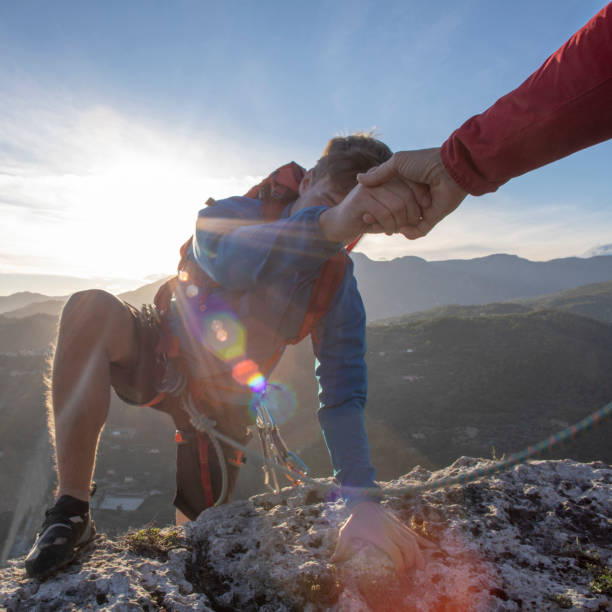 istock POV down arm to young man climbing up a rock face 1227241717