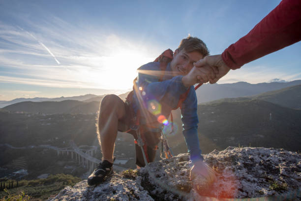 POV down arm to young man climbing up a rock face