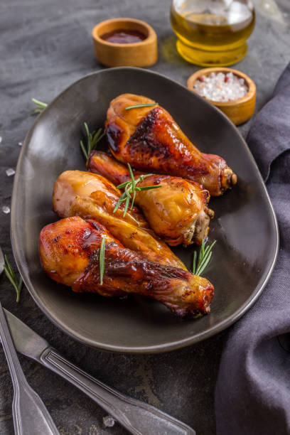 istock Chicken legs on black plate with red sauce and rosemary on black rustic background. 1227242659