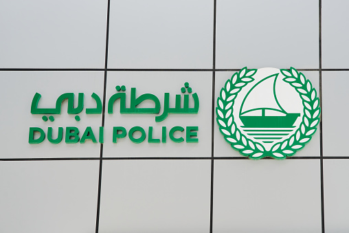 The Dubai Police Force logo. Logo of green color and features a boat on calm waters with writing in English and Arab