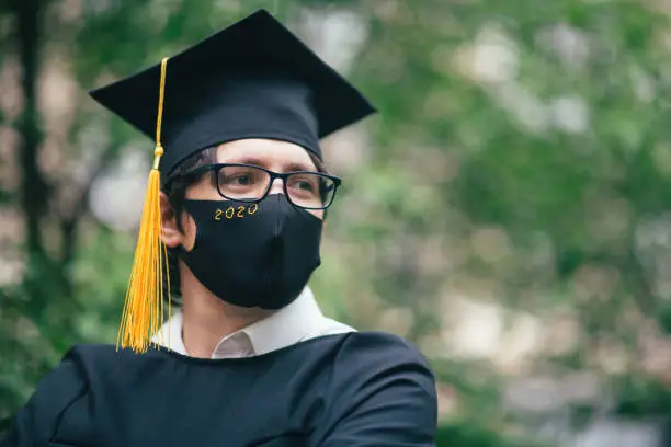 Photo of Class of 2020 graduate wearing protective mask and graduation gown and mask