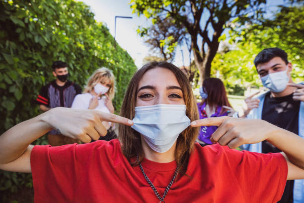 Group of teenagers posing showing their protective face masks Group of teenagers posing showing their protective face masks during Covid-19 Coronavirus epidemic spread. social distancing photos stock pictures, royalty-free photos & images