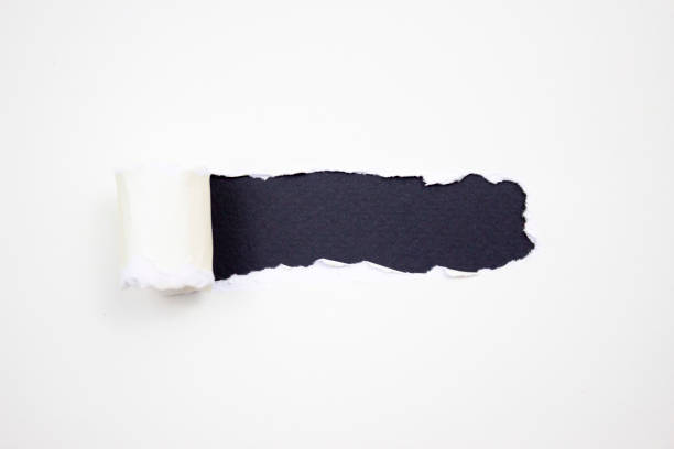 istock Torn white paper with jagged edges horizontally on a black background for your text. 1227246763