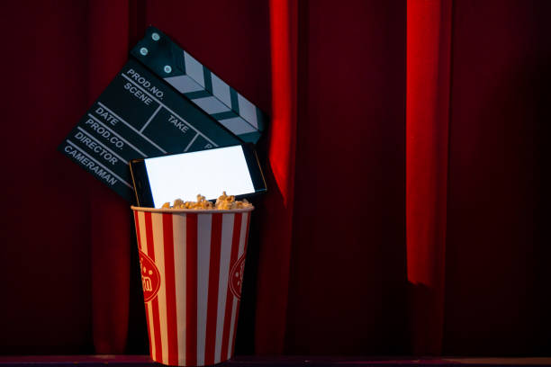 istock mobile phone with empty white bright screen with popcorn bucket and movie clapper board. Concept of streaming TV on internet phone. 1227256663