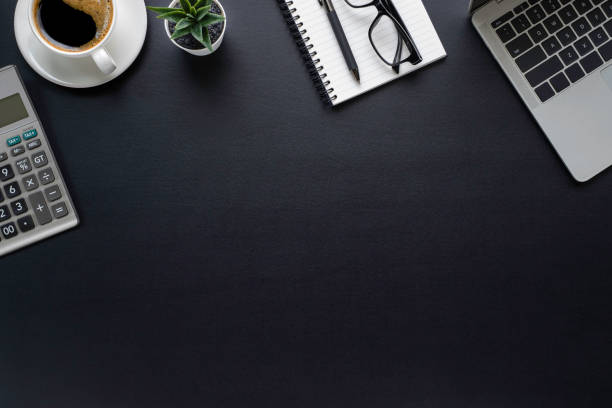 istock Workspace in office with black table. Top view from above of laptop with notepad and coffee. Desk for modern creative work of designer. Flat lay with blank copy space. Business and finance concept. 1227260219