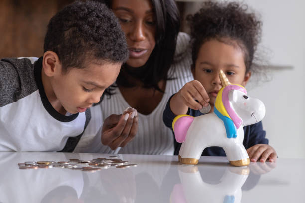 Two siblings save for a brighter future A beautiful mother of African American descent is teaching her two children of elementary school age the importance of saving money for a brighter future. The adorable children are depositing all of their pocket money to the unicorn shape money box. counting coins stock pictures, royalty-free photos & images