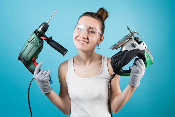 istock Smiling girl holding a drill and jigsaw in hands 1227261235