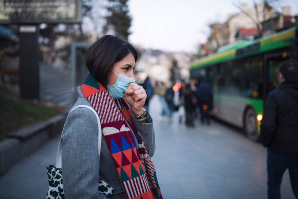 istock Woman With Protective Mask Cough On Bus Station. 1227261402