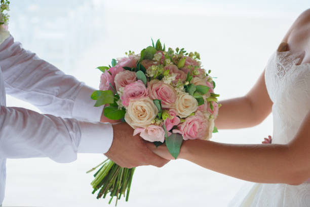 istock Newlyweds hold hands and a bouquet close-up. 1227262386