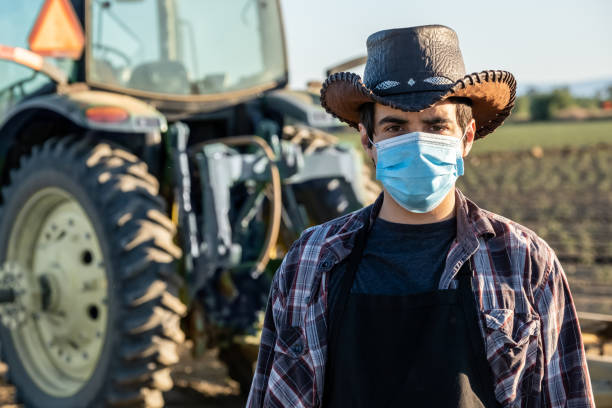 фермер работник носить защитную маску для лица из-за covid-19 профилактики заражения - spanish and portuguese ethnicity looking at camera waist up outdoors стоковые фото и изображения