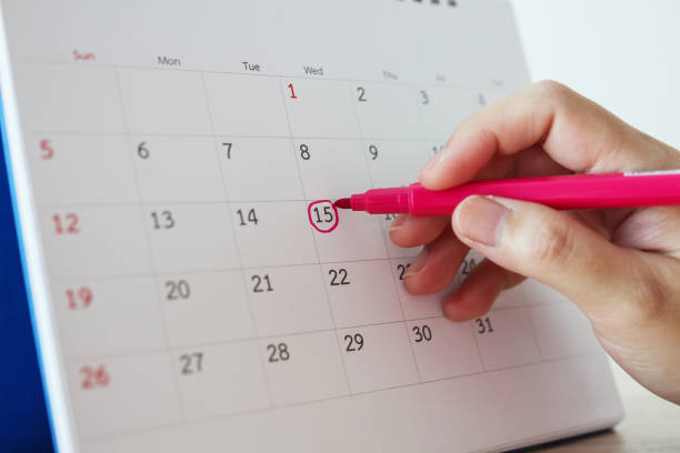 istock Hand with pen mark at 15th on calendar date 1227273553