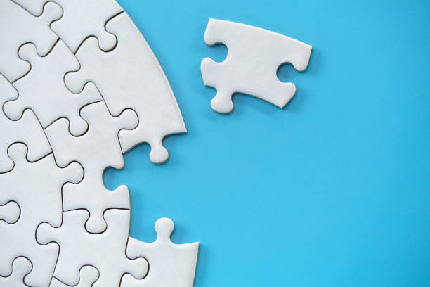 istock Unfinished white jigsaw puzzle on blue background with copy space. Business strategy teamwork and problem solving concept. 1227276409
