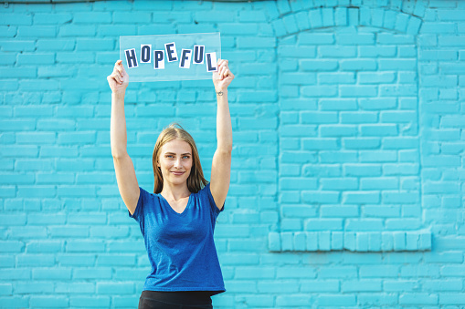 Urban Generation Z Female Outdoors With Handheld Signs Series with aqua blue brick wall background (Shot with Canon 5DS 50.6mp photos professionally retouched - Lightroom / Photoshop - original size 5792 x 8688 downsampled as needed for clarity and select focus used for dramatic effect)