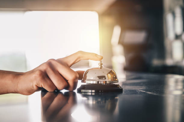 close-up of someone hand trying to call hotel reception by ringing front desk bell. - recepção imagens e fotografias de stock