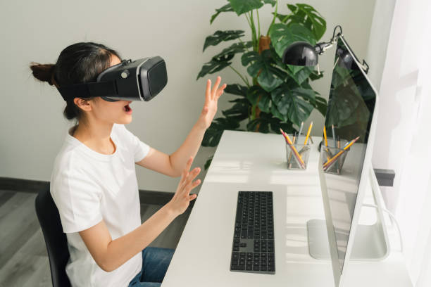 istock Excited young Asian woman using a virtual reality headset and joysticks, Concept connection and interfaces of digital technology. 1227277376