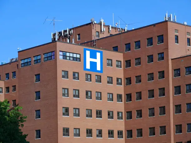 Photo of large brick hospital type building with block letter H sign