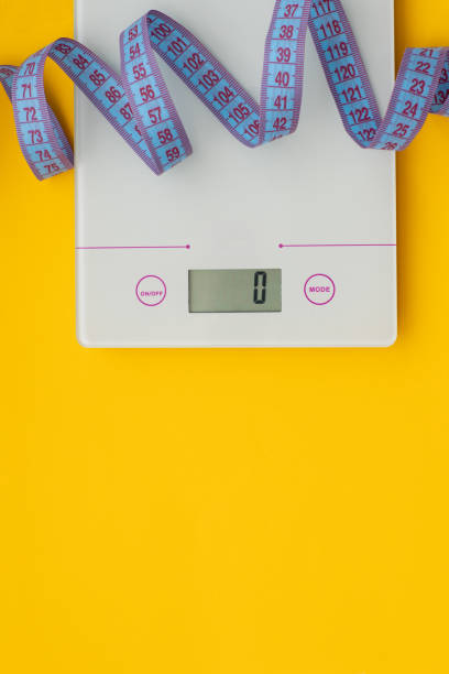istock Slim concept. Scale and measuring tape on bright yellow background top view, Flat lay, copy space 1227287794